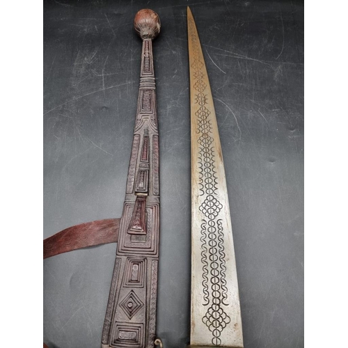 1755 - Ethnographica: an African sword and embossed leather scabbard, probably Nigerian, with 55cm blade.... 