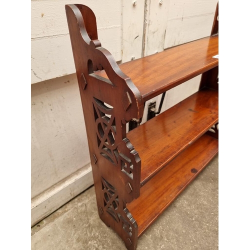 1026 - A late 19th/early 20th century mahogany fretwork hanging three tier shelf, 62cm wide.... 