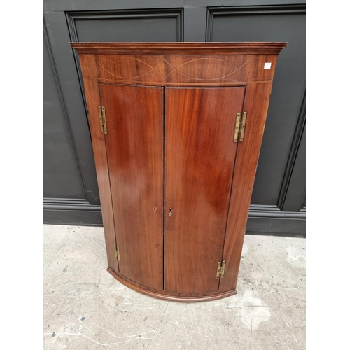 1039 - A George III mahogany and line inlaid bowfront hanging corner cupboard, 110cm high x 71cm wide.... 