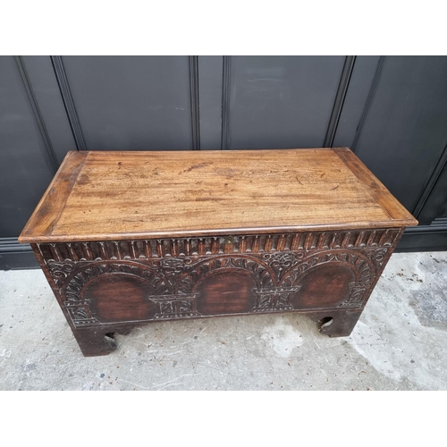 1056 - An early 18th century carved elm boarded coffer, 118.5cm wide. 