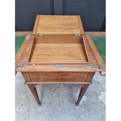 1064 - An unusual early 20th century oak writing table, by Asprey, the hinged top revealing a rising leathe... 