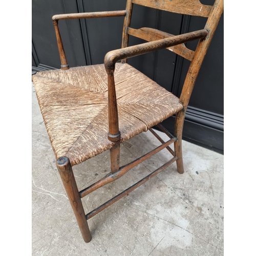 1083 - An antique ash and rush seated Sussex style elbow chair, with ladder back.