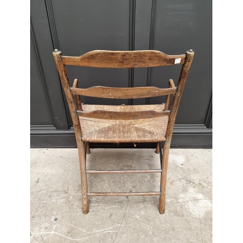 1083 - An antique ash and rush seated Sussex style elbow chair, with ladder back.