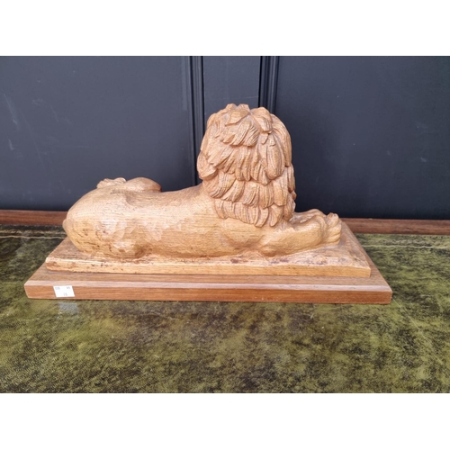 1152 - A carved oak recumbent lion, signed F Lang, on mahogany plinth, 46cm wide.