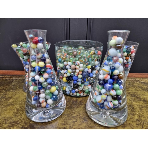 1159 - A large quantity of glass marbles, in five clear glass vases, (largest cracked).