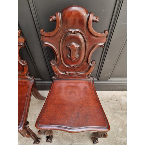 1085 - A pair of Victorian carved mahogany hall chairs. 