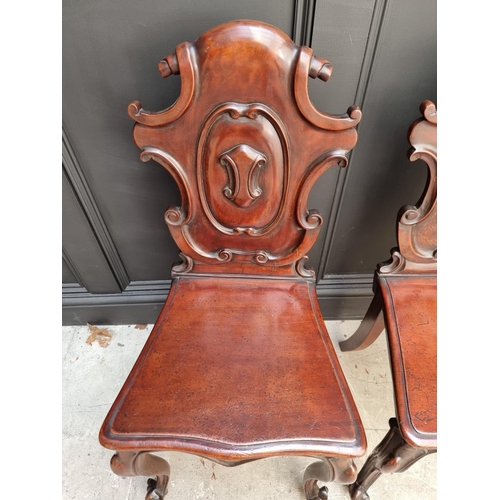 1085 - A pair of Victorian carved mahogany hall chairs. 