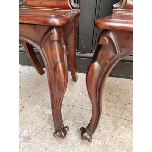 1085 - A pair of Victorian carved mahogany hall chairs. 