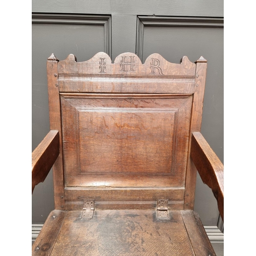 1098 - A 17th century panelled oak box seat open armchair, 106.5cm high x 60cm wide.  ... 