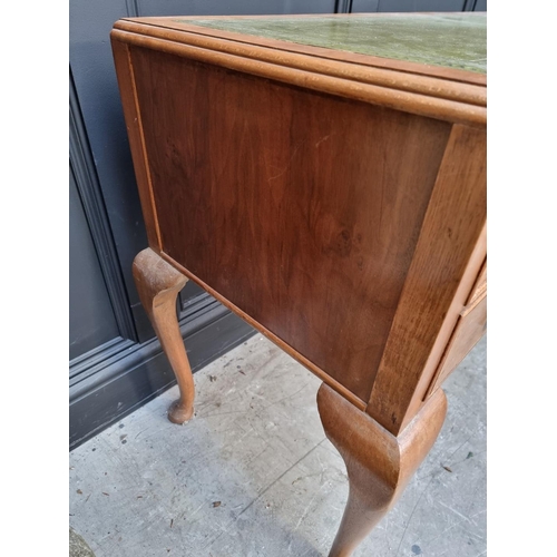 1106 - A 1930s walnut desk, with green leather inset surface and cabriole legs, 118.5cm wide.... 