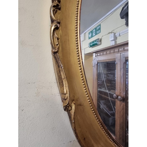 1129 - A pair of antique gilt framed oval wall mirrors, 66 x 53cm, (s.d. to mouldings).