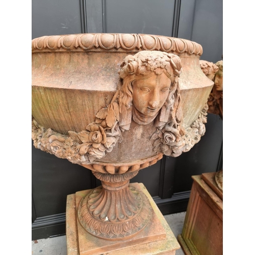 1132 - A large and impressive pair of red composition stone urns and pedestals, the urns 81cm high x 81cm w... 