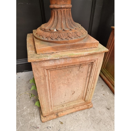 1132 - A large and impressive pair of red composition stone urns and pedestals, the urns 81cm high x 81cm w... 