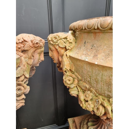 1132 - A large and impressive pair of red composition stone urns and pedestals, the urns 81cm high x 81cm w... 