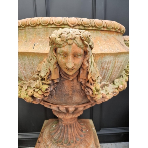 1132 - A large and impressive pair of red composition stone urns and pedestals, the urns 81cm high x 81cm w... 