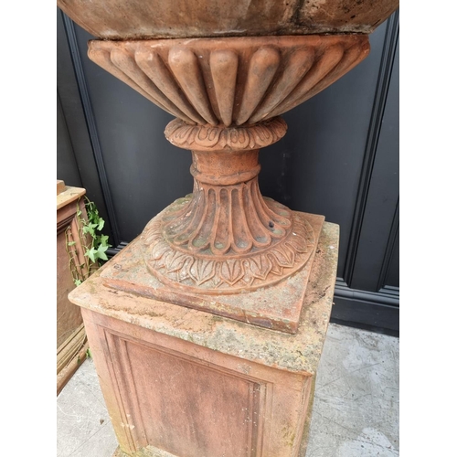 1132 - A large and impressive pair of red composition stone urns and pedestals, the urns 81cm high x 81cm w... 