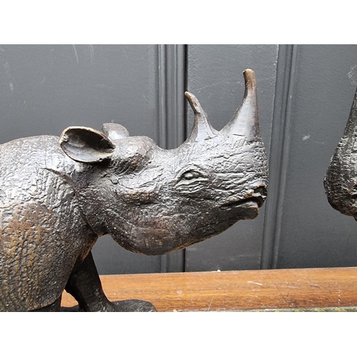 1389 - Two bronze rhinoceros, each bearing signature, on marble bases, 27cm long, (lost tip of one hor... 