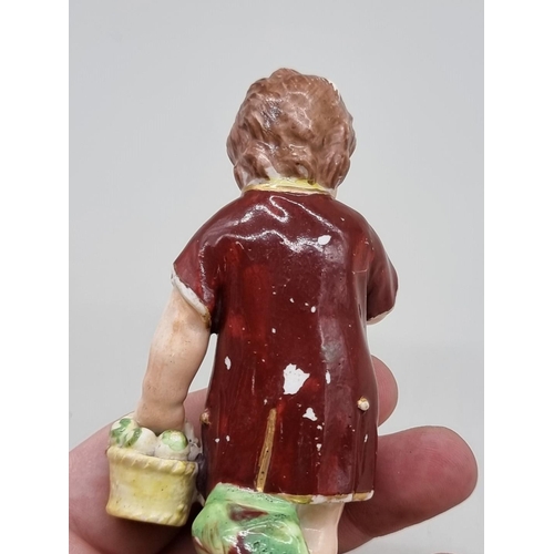 1254 - An early 19th century Derby porcelain figure of a boy eating an apple, incised No.101, 11cm high.... 