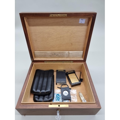 1498 - A walnut cigar humidor, 28cm wide; together with two Zippo lighters; a black leather cigar slee... 