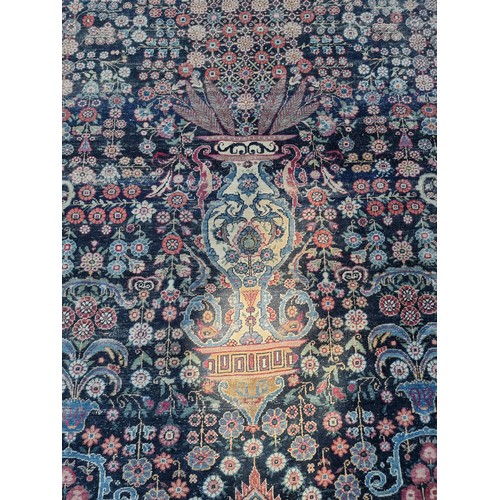 1001 - A large Persian rug, having central floral urn, with floral scrolls to side, borders decorated with ... 