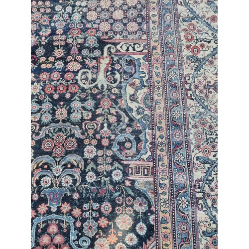 1001 - A large Persian rug, having central floral urn, with floral scrolls to side, borders decorated with ... 