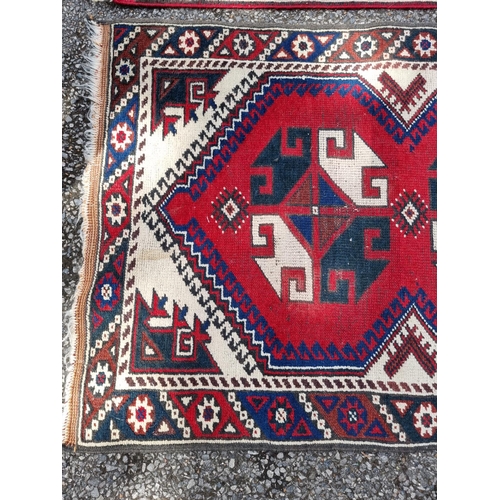 1003 - A small tribal rug, with floral borders, 119 x 76cm wide; together with another similar rug, 110 x 7... 