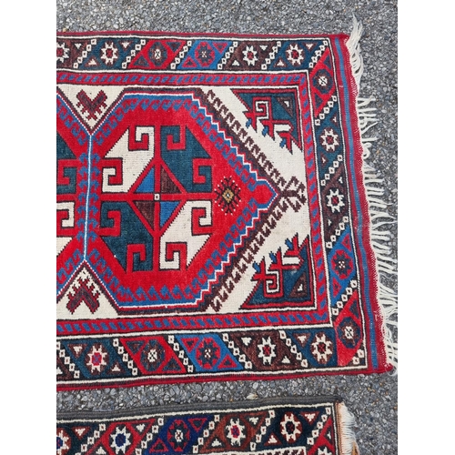 1003 - A small tribal rug, with floral borders, 119 x 76cm wide; together with another similar rug, 110 x 7... 
