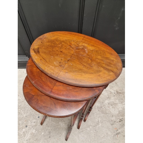 1057 - A nest of three 1930s walnut oval occasional tables, largest 56cm wide. 