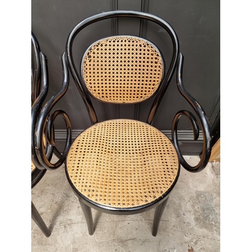 1085 - A set of four ebonized and cane bentwood elbow chairs, labelled 'Dinette'.