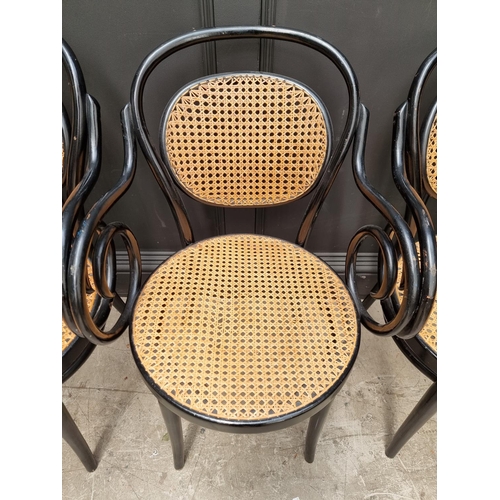 1085 - A set of four ebonized and cane bentwood elbow chairs, labelled 'Dinette'.