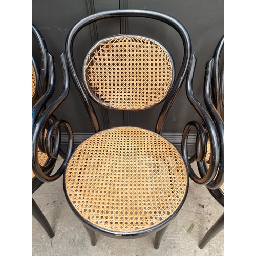 1085 - A set of four ebonized and cane bentwood elbow chairs, labelled 'Dinette'.