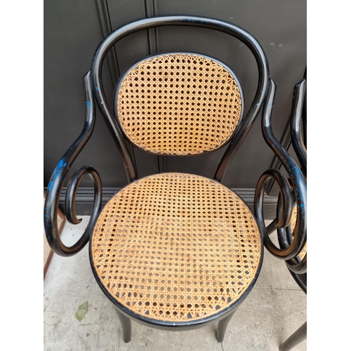 1085 - A set of four ebonized and cane bentwood elbow chairs, labelled 'Dinette'.