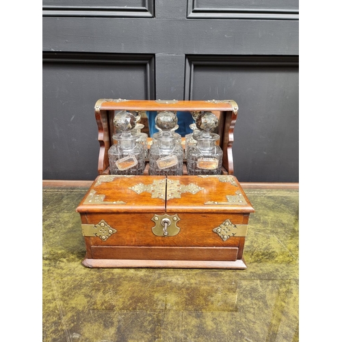 1119 - A circa 1900 oak and electroplate mounted combined tantalus, cigar and games box, the apron drawer w... 