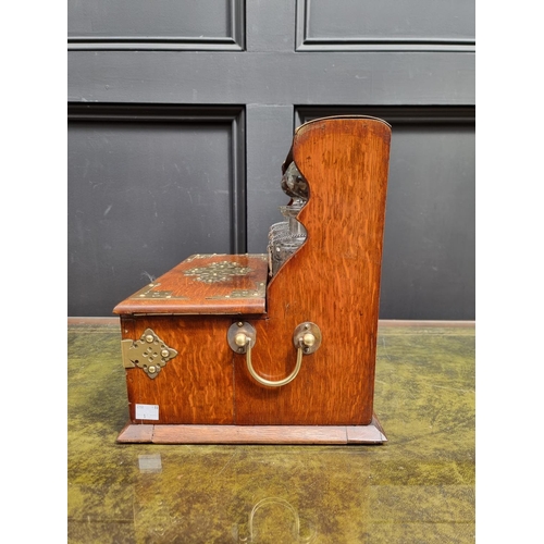 1119 - A circa 1900 oak and electroplate mounted combined tantalus, cigar and games box, the apron drawer w... 