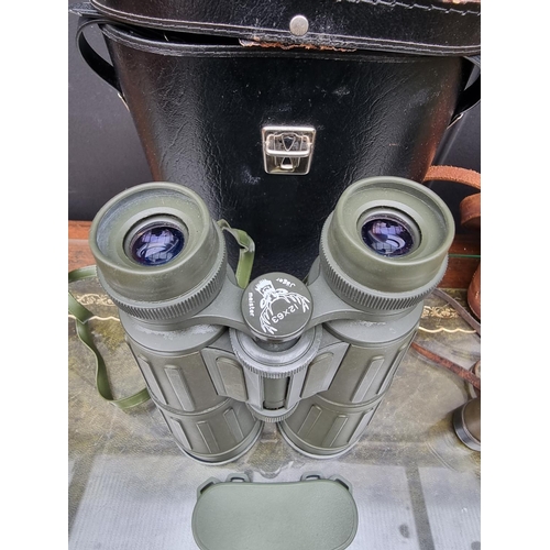 1307 - A pair of Seeadler 12x63 binoculars, in case; together with another pair of field glasses, in leathe... 