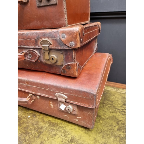 1416 - Three vintage leather suitcases, largest 66.5cm wide. 