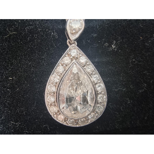 135 - A pear shaped diamond pendant, of approximately 1.75ct, surrounded by a border of seventeen brillian... 