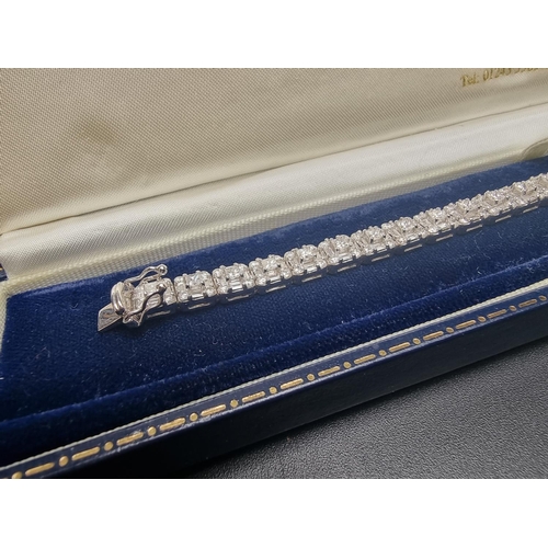 142 - A white gold and diamond encrusted bracelet, set with two-hundred and sixty-one baguette cut, double... 