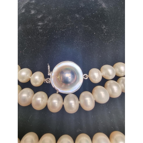 143 - A freshwater pearl necklace, having mother of pearl and white metal clasp stamped '925', 85cm long.... 