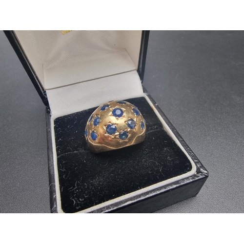 163 - A yellow metal ring, of domed design pave set fifteen sapphires, size J.