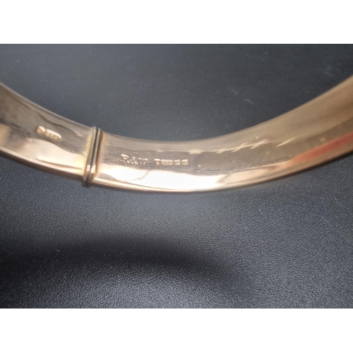 195 - A 9ct gold hinged bangle, having chased floral decoration to one side, Birmingham 1973, 19.1g.... 