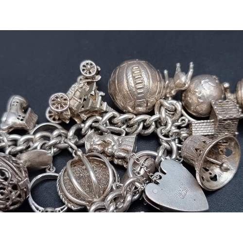 205 - A charm bracelet, having padlock clasp, by Georg Jensen Ltd, stamped 'silver', with twenty two attac... 