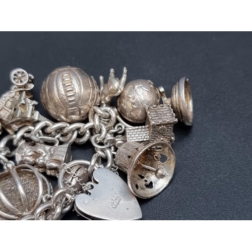 205 - A charm bracelet, having padlock clasp, by Georg Jensen Ltd, stamped 'silver', with twenty two attac... 