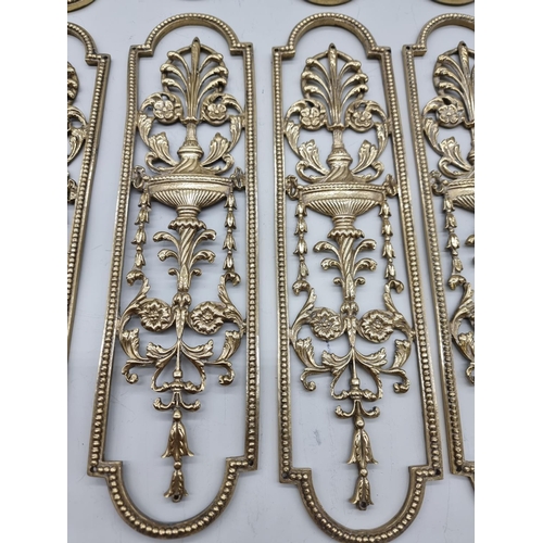 1391 - A set of seven cast brass door plates, 29cm long; and one further similar example. ... 