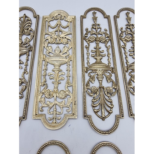 1391 - A set of seven cast brass door plates, 29cm long; and one further similar example. ... 