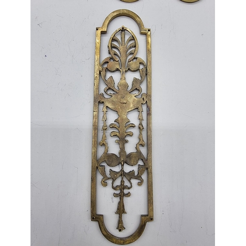 1391 - A set of seven cast brass door plates, 29cm long; and one further similar example. ... 