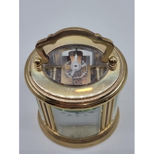 1520 - A small brass oval carriage timepiece, the dial inscribed 'Rapport', height including handle 10... 