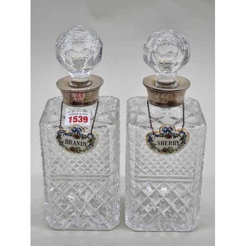 1539 - A pair of silver mounted cut glass decanters and stoppers, each with Crown Staffordshire label. ... 