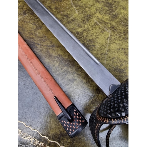 1703 - A reproduction basket hilt sword and leather scabbard, with 83cm blade.