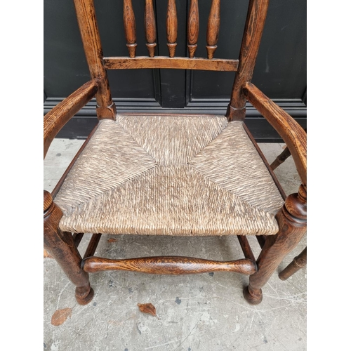 1080 - A small Victorian ash and rush spindle back elbow chair; together with another wheelback chair. (2)... 